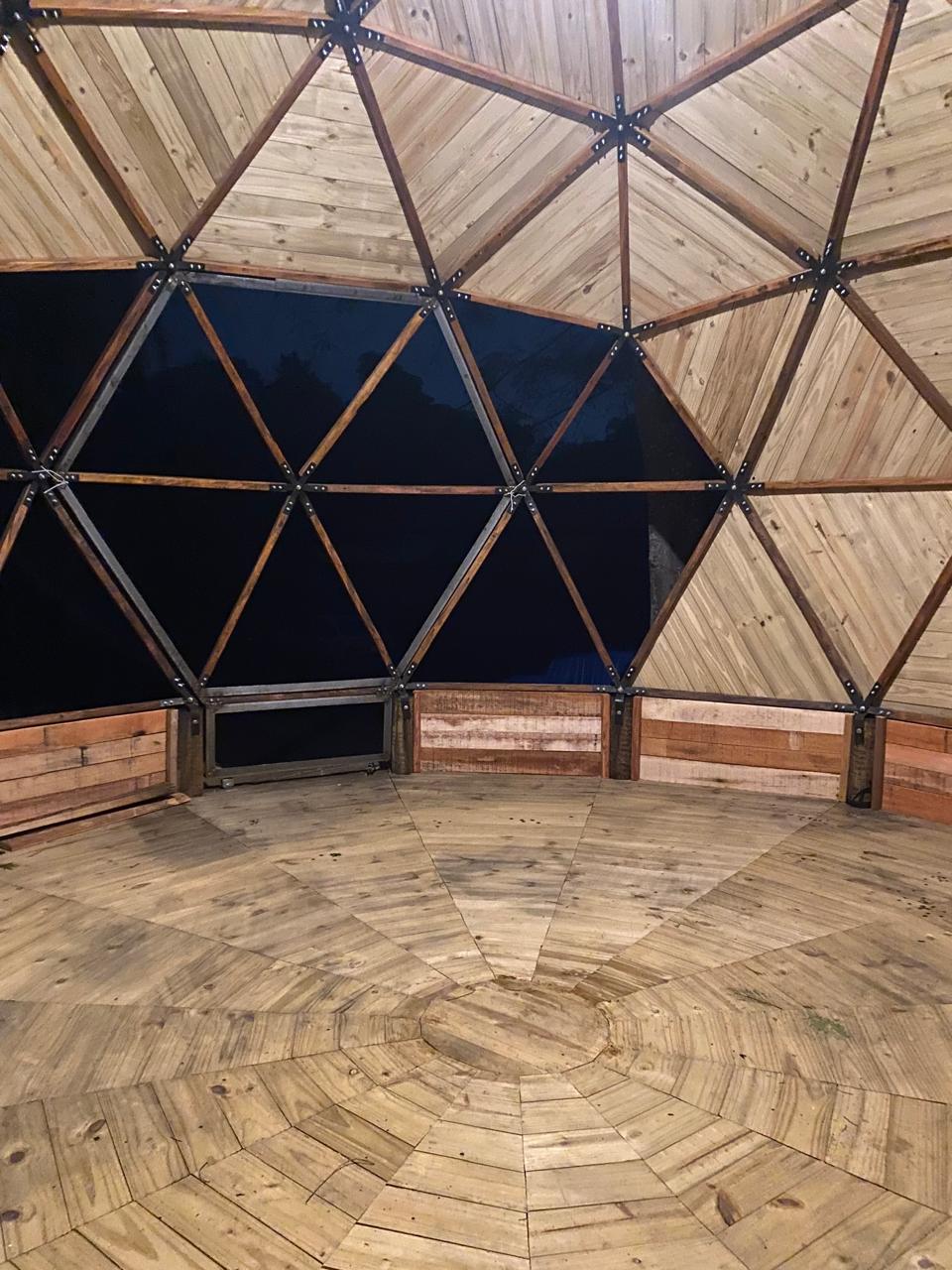 Interior do domo com estrutura triangular e piso de madeira